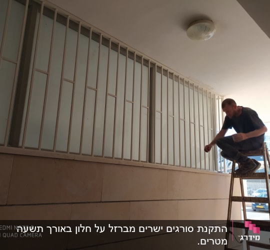 אדם על סולם מתקין מסגרת מתכת לחלון
